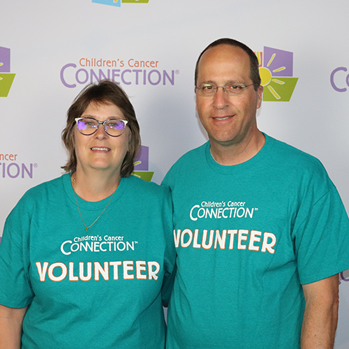 two volunteers posing in front of a CCC logo backdrop