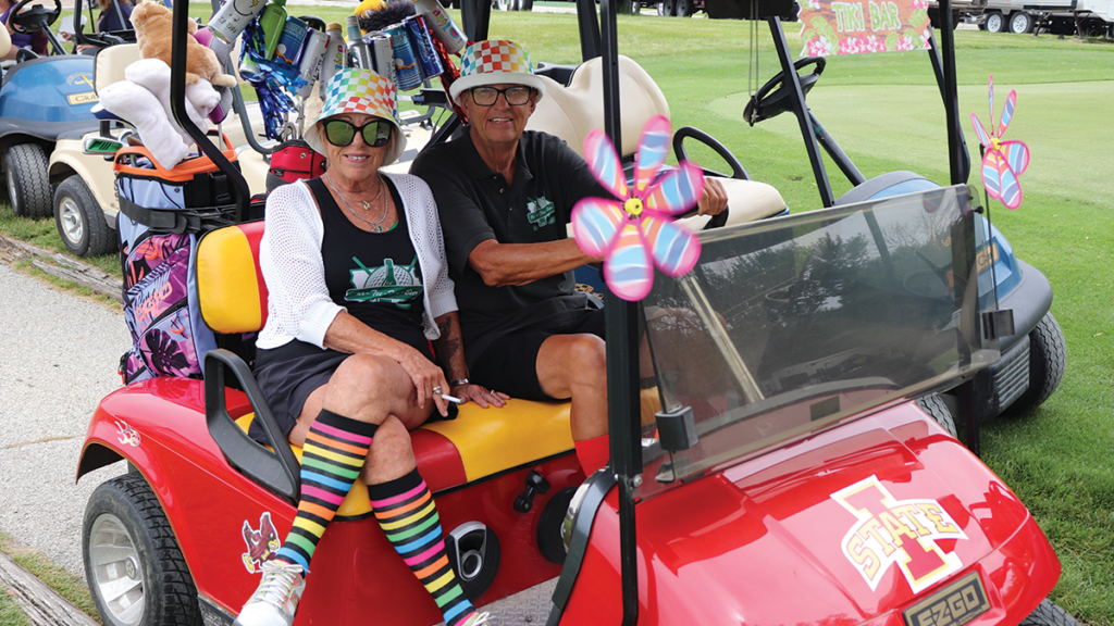 two golfers in a fun golf cart with colorful costumes