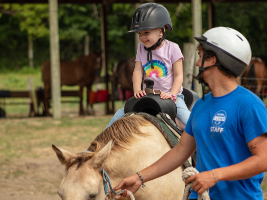girl smiling on horse at summer camp